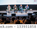 Panel discussion with four speakers on stage in front of an engaged audience 133931858