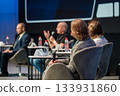 Panel discussion at conference featuring speakers audience microphones water bottles and notes  133931860