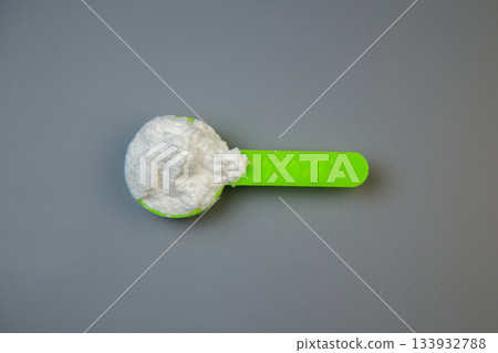 Green measuring spoon holds white powdery substance against gray backdrop, emphasizing accuracy in cooking and baking, perfect for culinary enthusiasts and professionals Green measuring spoon holds white powdery substance against gray backdrop, emphasizing accuracy in cooking and baking, perfect for culinary enthusiasts and professionals 133932788