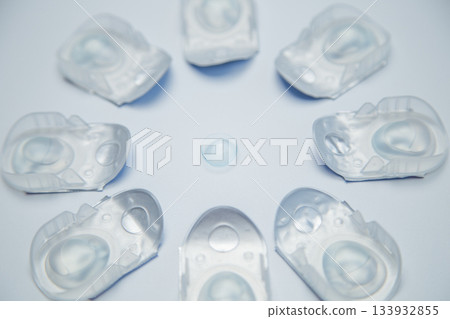 Creative flower layout of one-day contact lenses in disposable protective packaging, in the center is a transparent contact lens on a white background. The concept of ophthalmology, vision correction Creative flower layout of one-day contact lenses in disposable protective packaging, in the center is a transparent contact lens on a white background. The concept of ophthalmology, vision correction 133932855