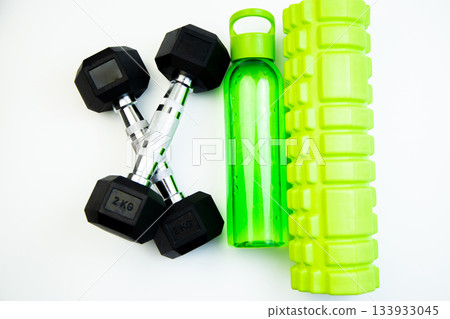 Collection of fitness accessories featuring black dumbbells, a green water bottle, and a foam roller on a clean white background, ideal for workout motivation Collection of fitness accessories featuring black dumbbells, a green water bottle, and a foam roller on a clean white background, ideal for workout motivation 133933045
