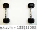 Two black dumbbells with silver accents are arranged symmetrically on a white background, emphasizing fitness and exercise with ample copy space for creative use 133933063