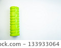 Vibrant green foam roller placed on a white background, highlighting its unique texture and shape, ideal for muscle recovery and fitness routines 133933064