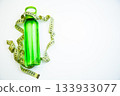 A vibrant green water bottle is artistically placed with measuring tape, representing health and fitness concepts, with clear copy space for creative use 133933077