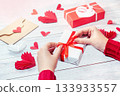 girl ties a red ribbon on a gift box, valentine's day 133933557