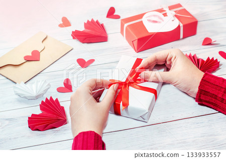girl ties a red ribbon on a gift box, valentine's day girl ties a red ribbon on a gift box, valentine's day 133933557