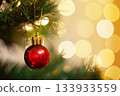 red Christmas ball on a spruce branch with a background of blurry bokke  133933559
