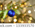 Christmas toy against the background of green spruce branches with golden bokeh 133933570