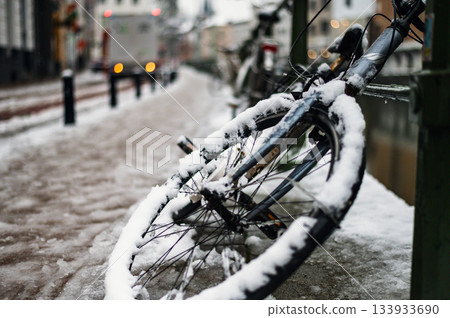 Black bicycle under the snow outside after a snowfall in town. 133933690