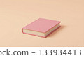Minimalist composition with a closed pink hardcover book placed on a soft pastel peach background, emphasizing simplicity, calm, and modern design aesthetic. 133934413