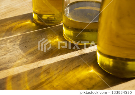 olive oil bottls with golden reflections on wooden table close up 133934550