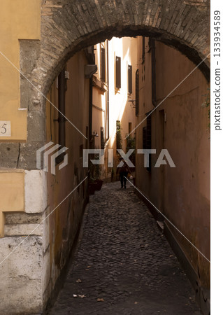 narrow cobblestone alley viewed through ancient brick archway in Rome narrow cobblestone alley viewed through ancient brick archway in Rome 133934589