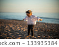 Small baby girl in a hat having fun on Baltic sea beach.  133935384
