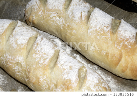 Close up of fresh homemade baguette sub rolls bread that has come out of the oven and still on baking tray 133935516