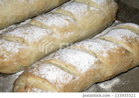 Close up of fresh homemade baguette sub rolls bread that has come out of the oven and still on baking tray Close up of fresh homemade baguette sub rolls bread that has come out of the oven and still on baking tray 133935521