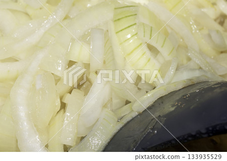 Close up of chopped frying onions in a metal pan cooking Close up of chopped frying onions in a metal pan cooking 133935529
