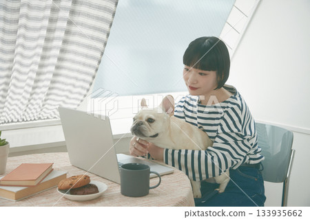 A woman working on a PC and a dog A woman working on a PC and a dog 133935662