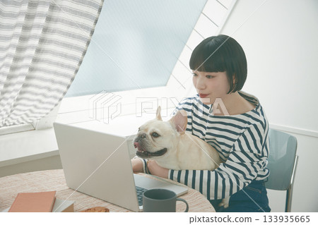A woman working on a PC and a dog 133935665