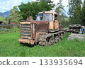 An old abandoned Soviet tractor overgrown with grass 133935694