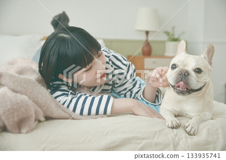 Dog and woman lying on bed Dog and woman lying on bed 133935741