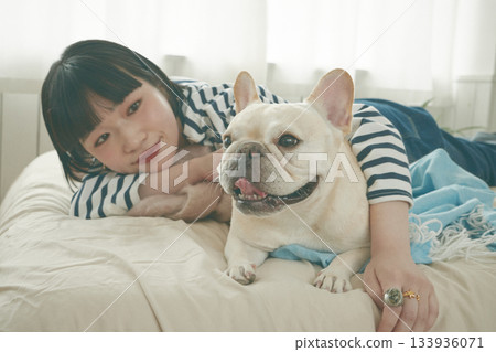 Dog and woman lying on bed Dog and woman lying on bed 133936071