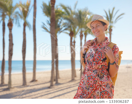 Woman in dress strolls through colorful streets of Spanish coastal town of La Vila Joiosa or Villajoyosa. sunny winter atmosphere highlights charm of Mediterranean architecture and quiet seaside life 133936287