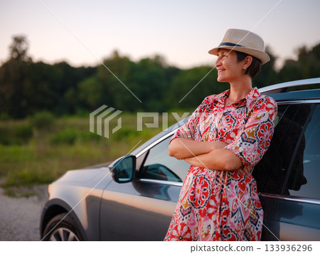 Traveler woman in red ethnic dress and hat drives car through scenic countryside of Croatia in summer. Surrounded by lush fields and forests, she enjoys peaceful and adventurous road trip Traveler woman in red ethnic dress and hat drives car through scenic countryside of Croatia in summer. Surrounded by lush fields and forests, she enjoys peaceful and adventurous road trip 133936296