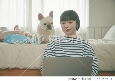 一位女士正在用電腦，她的寵物也在旁邊。 133936304