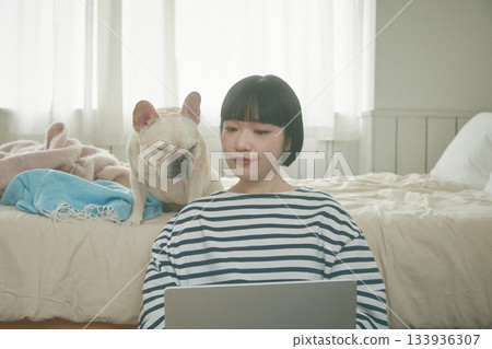 一位女士正在用電腦，她的寵物也在旁邊。 133936307