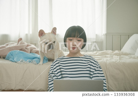 一位女士正在用電腦，她的寵物也在旁邊。 133936308