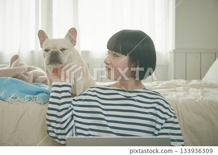 一位女士正在用電腦，她的寵物也在旁邊。 133936309