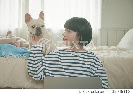 一位女士正在用電腦，她的寵物也在旁邊。 133936310