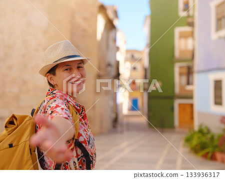 Woman in dress strolls through colorful streets of Spanish coastal town of La Vila Joiosa or Villajoyosa. sunny winter atmosphere highlights charm of Mediterranean architecture and quiet seaside life 133936317