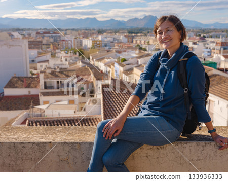 Young woman exploring historic castle in Denia, Alicante province, Spain, scenic views of town below, set against cooler season backdrop. blend of history and tranquility in timeless setting. Young woman exploring historic castle in Denia, Alicante province, Spain, scenic views of town below, set against cooler season backdrop. blend of history and tranquility in timeless setting. 133936333