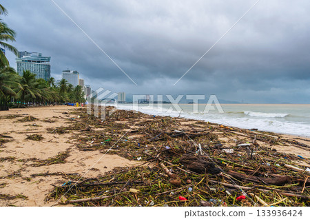 Piles of garbage and waste on the beach by sea after a storm in cloudy rainy weather. Environmental disaster on the waterfront of Nha Trang resort town in Vietnam Piles of garbage and waste on the beach by sea after a storm in cloudy rainy weather. Environmental disaster on the waterfront of Nha Trang resort town in Vietnam 133936424