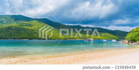 sandy beach on tropical island in a bay by sea on summer. Luxury exotic resort in Asia. Landscape panorama with a view of coast by the ocean sandy beach on tropical island in a bay by sea on summer. Luxury exotic resort in Asia. Landscape panorama with a view of coast by the ocean 133936439
