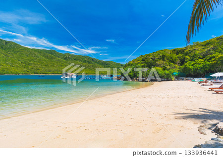 sandy beach in azure bay by sea in summer. A tropical luxury resort on an island for travel. landscape with exotic ocean view sandy beach in azure bay by sea in summer. A tropical luxury resort on an island for travel. landscape with exotic ocean view 133936441
