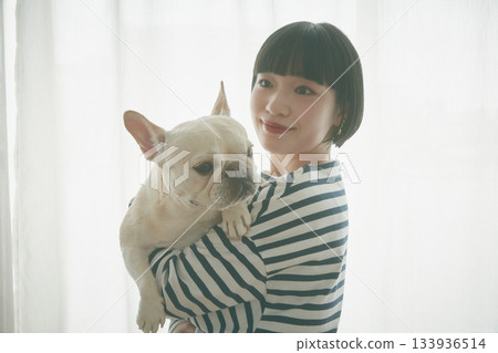 Woman holding a dog by the window Woman holding a dog by the window 133936514