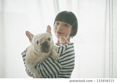 Woman holding a dog by the window Woman holding a dog by the window 133936515