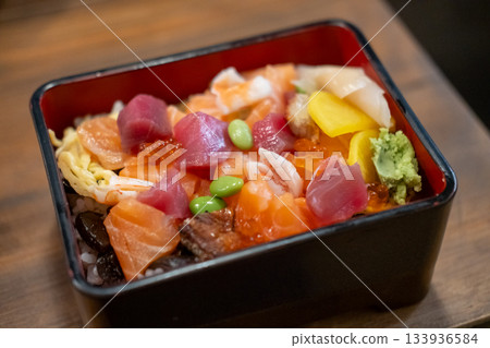 Donburi, a Japanese rice bowl dish of seafood. Including raw fish such as sliced salmon, and tuna. 133936584