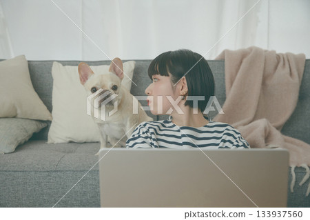 一位女士正在電腦前工作，一隻狗在一旁看著她。 133937560