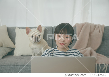 一位女士正在電腦前工作，一隻狗在一旁看著她。 133937562