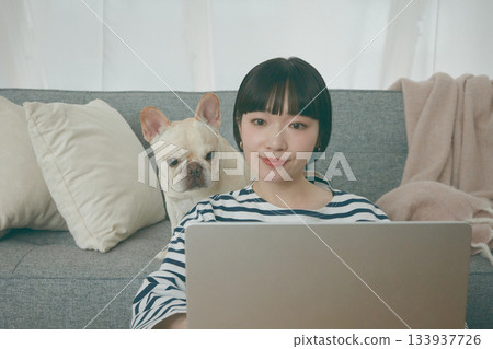 一位女士正在電腦前工作,一隻狗在一旁看著她。 一位女士正在電腦前工作,一隻狗在一旁看著她。 133937726