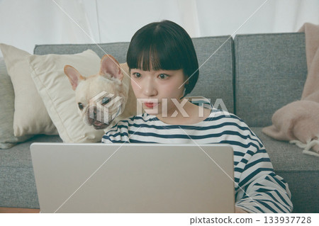 一位女士正在電腦前工作，一隻狗在一旁看著她。 133937728