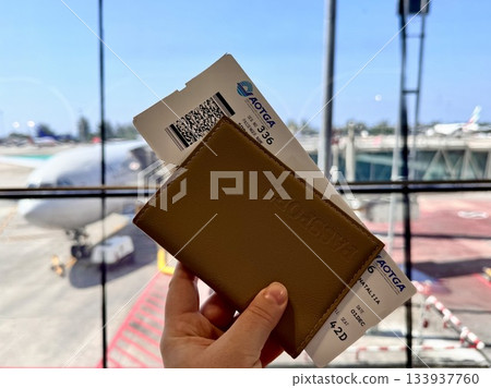 Leather-covered passport and boarding pass on the background of airplanes at Phuket airport 133937760