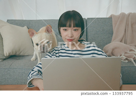 一位女士正在電腦前工作,一隻狗在一旁看著她。 一位女士正在電腦前工作,一隻狗在一旁看著她。 133937795