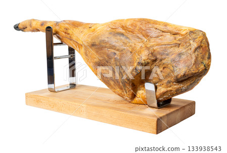 Cured Spanish jamon ham leg resting on holder isolated on white background Cured Spanish jamon ham leg resting on holder isolated on white background 133938543