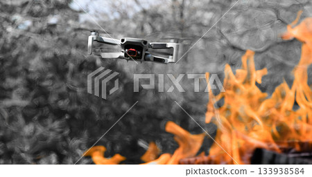 Flying drone Quadcopter with camera pointed at viewer outdoor in a bright fire in the foreground spurts of flame 133938584