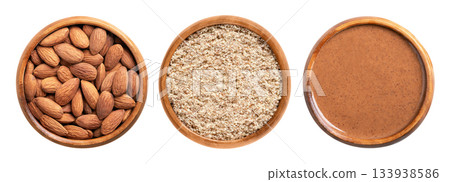 Whole almonds, ground, and almond butter, in wooden bowls. From left to right dried almonds with skin, ground unpeeled almonds, and processed into a paste. Prunus dulcis. Isolated, from above. Photo 133938586