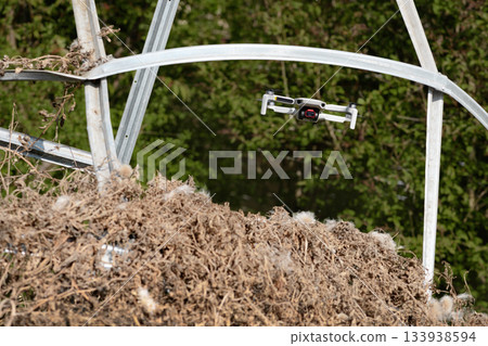 Small Flying Quadcopter Drone in flight mode with camera pointed at viewer outdoor destroyed rebar frame 133938594